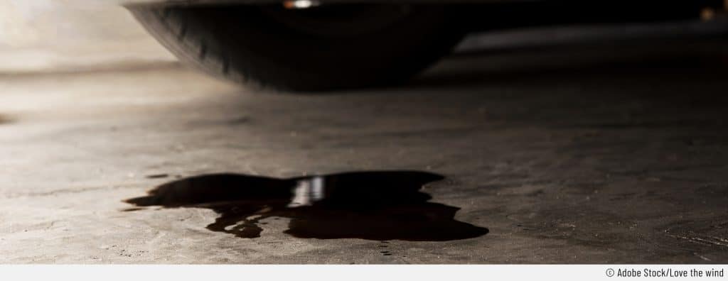 Auf dem Bild ist ein Ölfleck unter einem Auto zu sehen.