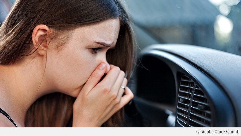 Auf dem Bild sieht man, wie eine Frau sich die Nase zuhält, weil aus der Lüftung ihres Autos ein unangenehmer Geruch kommt, weil die Klimaanlage desinfiziert werden muss.