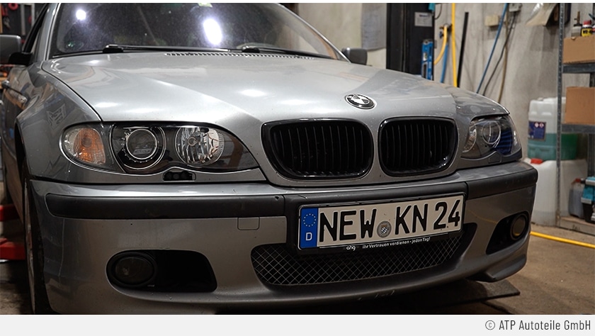 Es handelt sich um eine Nahaufnahme der Frontscheinwerfer des nun wie neu aussehenden  silberfarbenen 3er BMW-Autos. Auch das Kennzeichen spricht Bände: NEW KN 24.