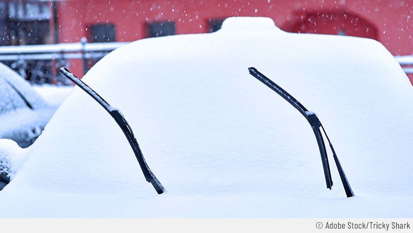 Auf dem Bild ist ein zugeschneites Auto zusehen. Die Scheibenwischer sind hochgeklappt, damit diese nicht an der Windschutzscheibe festfrieren.