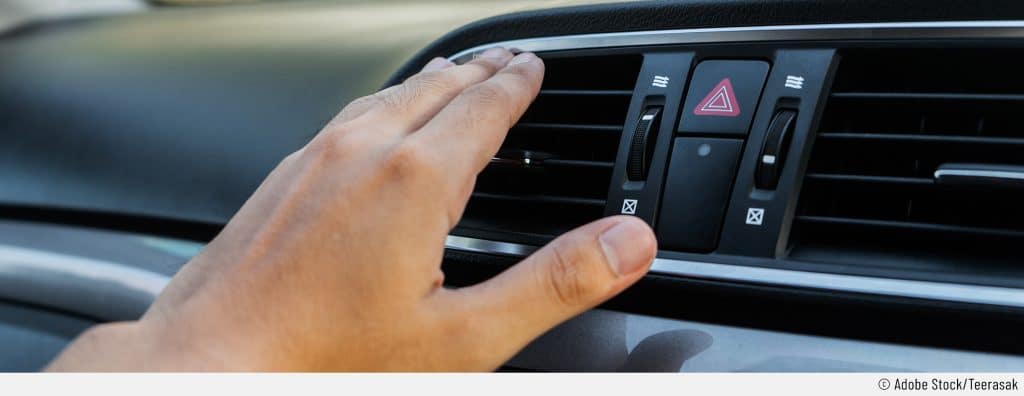 Auf dem Bild ist eine Hand vor dem Lüftungsschacht eines Autos zu sehen. Die Person versucht, die Klimaanlage zu testen.