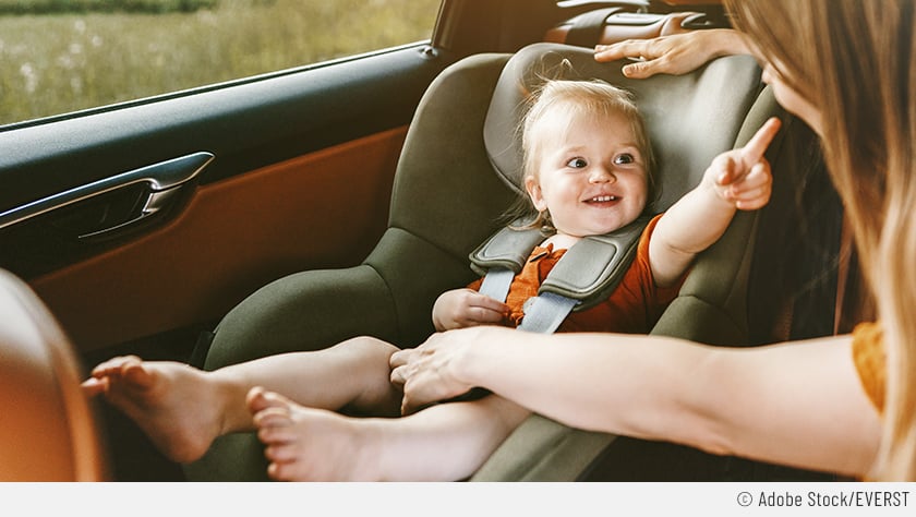 Eine Mutter schnallt gerade ihr Baby in einem speziellen Kindersitz an, um die lange Autofahrt so angenehm und sicher wie möglich zu gestalten.
