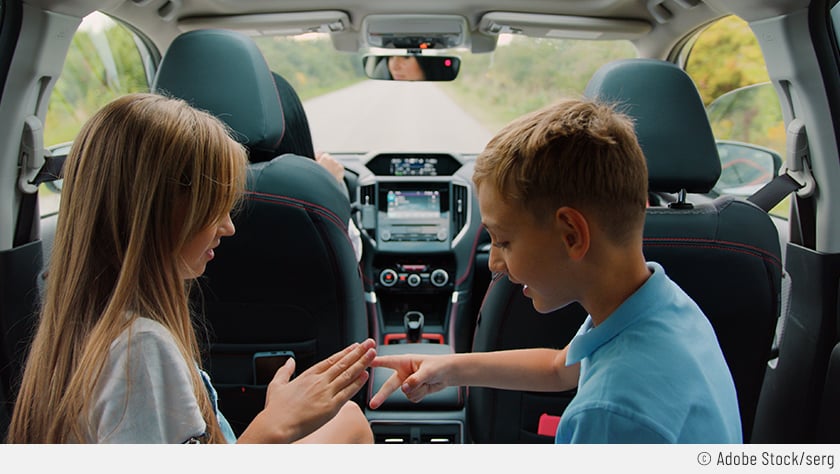 Zwei Kinder spielen während einer langen Autofahrt „Schere, Stein, Papier“, damit es nicht zu langweilig wird.