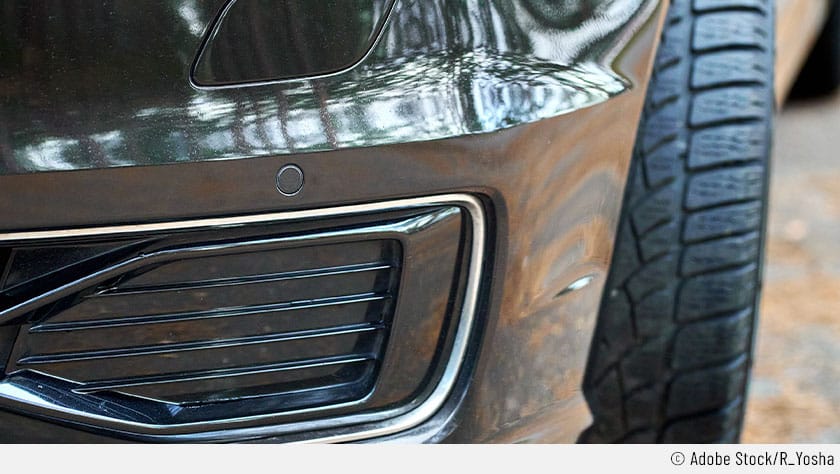 Auf dem Bild sind Sensoren an einer schwarzen Fahrzeugfront zu erkennen, die bei einem Defekt die VW-Fehlermeldung "ACC & Fronst Assist nicht verfügbar" hervorrufen können.